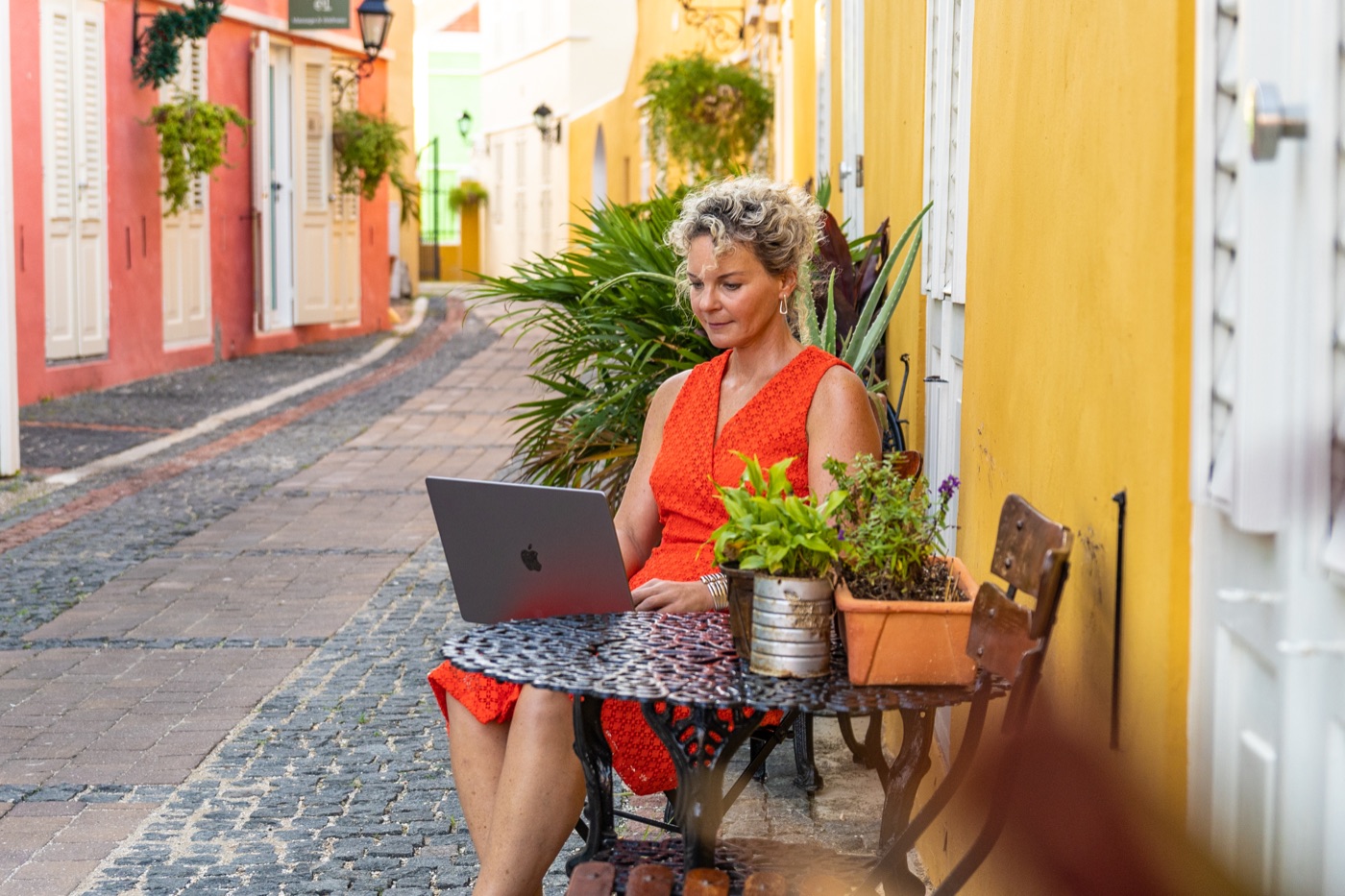 Daisy Kuipers werkt online aan marketing voor de kinderopvang, met haar laptop aan een tafeltje in een kleurrijk straatje